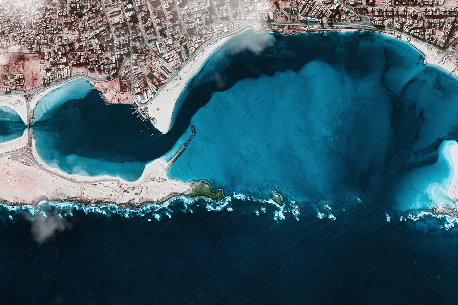 Aerial satellite photograph of an inlet next to a coastal city.